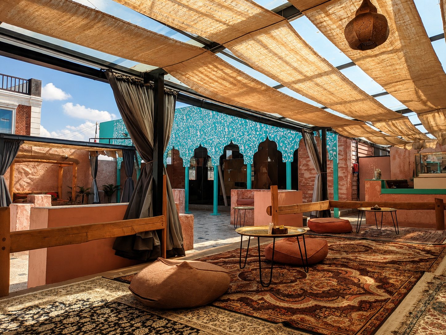 Courtyard lounge with rugs, low tables and a turquoise patterned wall