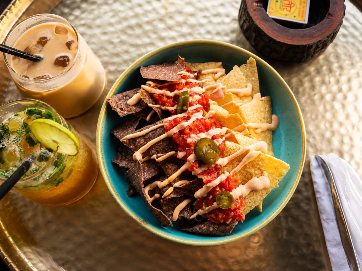 A colorful spread of chips, three dips and iced drinks